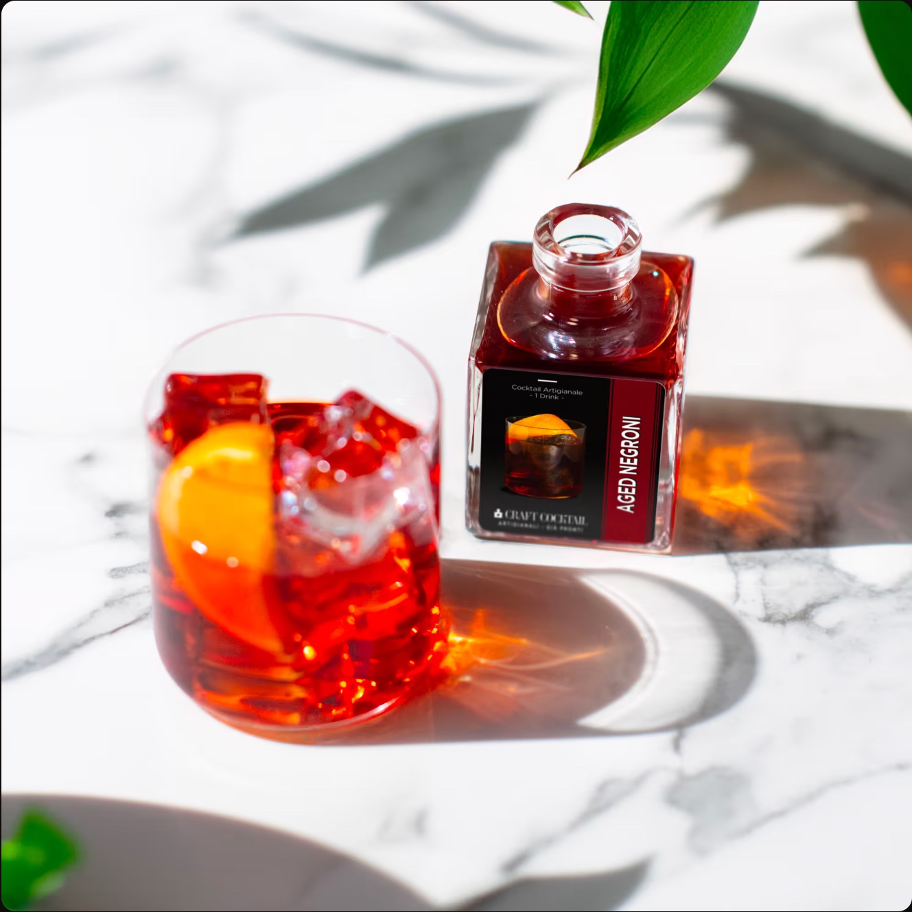 Cocktail rosso e bottiglia su un piano di marmo