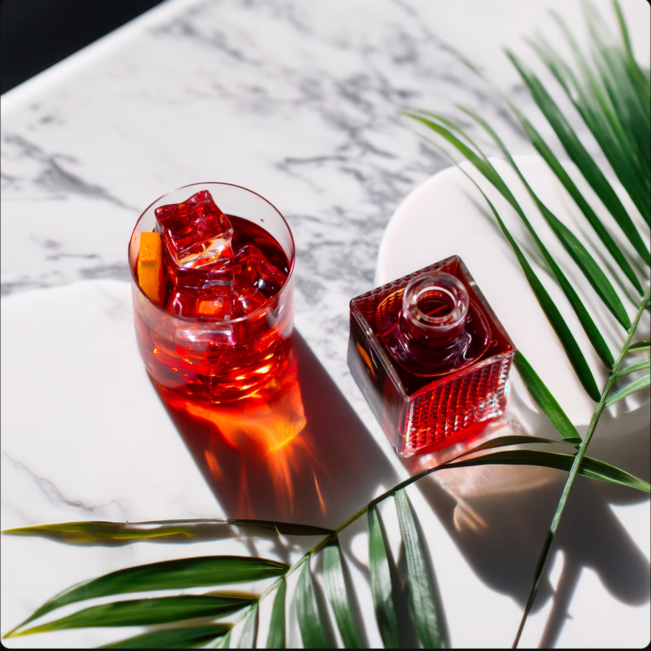 Cocktail rosso e bottiglia incorniciati da foglie